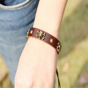 Punk leather bracelet with skull rivets and wooden beads on wrist with denim background