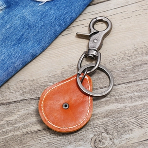 Vintage brown leather keychain with bronze metal hook on wooden background