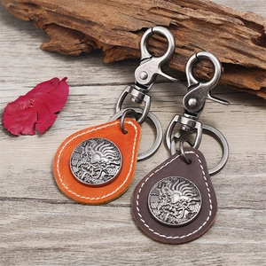 Vintage leather dragon keychain set with bronze carabiners on a natural wooden background