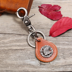 Vintage eagle emblem leather keychain with rustic bronze lobster clasp on wood background
