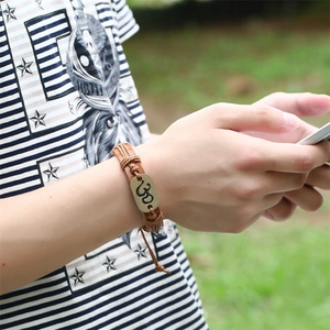Bracelet vintage en cuir tressé avec pendentif symbole Om en bronze porté sur un poignet
