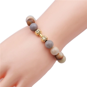 Beaded malachite bracelet with matte gold dumbbell charm shown on a hand model