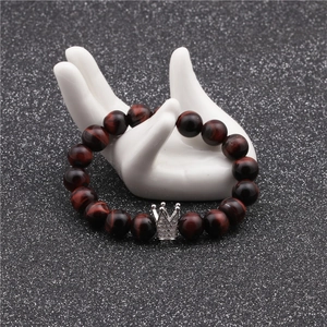 Bracelet en Oeil de Tigre rouge 10mm avec couronne en zircon argenté sur un modèle de main