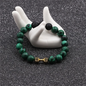 Macro detail of malachite and lava stone beads with a golden live lift dumbbell charm
