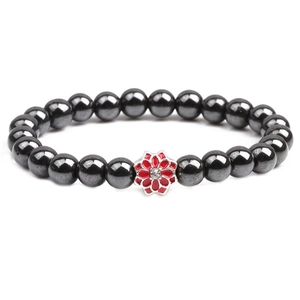 Detail of magnetic hematite beaded bracelet with a red enamel flower charm and crystal