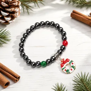 Dettaglio del bracciale di perle di ematite con ciondolo ghirlanda di Natale e fiocco rosso lucido