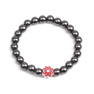 Detail of hematite beaded bracelet featuring a red floral charm with a small white crystal
