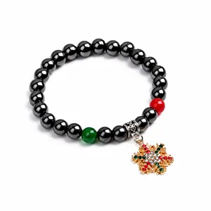 Dettaglio del bracciale di ematite con ciondolo a fiocco di neve dorato e accenti festivi