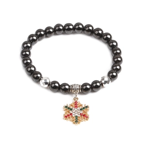 Detailaufnahme eines festlichen Weihnachtsperlenarmbands mit goldenem Schneeflocken-Anhänger