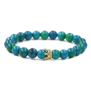 Dettaglio del bracciale con perle marmorizzate blu-verdi e ciondolo a corona dorata