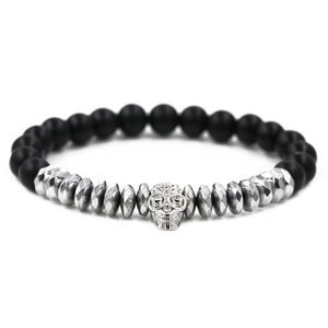 Makroaufnahme eines matt schwarzen Lavastein-Perlenarmbands mit silbernem Totenkopf