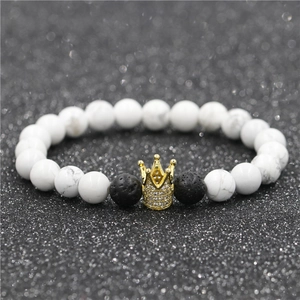 Macro shot of white turquoise beads with a golden crown charm and black lava stones