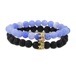 Blaues Perlenarmband und schwarzes Lavastein-Kronen-Set für Paare auf weißem Hintergrund