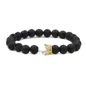 Detailed close-up of volcanic stone bracelet with golden crown and white moonstone bead