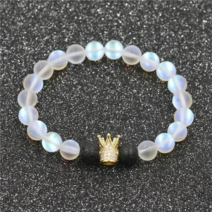 Detailed macro of a beaded bracelet with moonstone, lava stone beads, and a gold crown charm