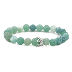 Detailed macro view of green matte volcanic stone beads and silver crown charm on bracelet