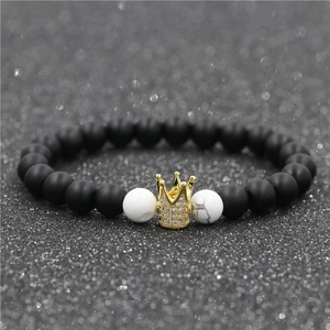 Gros plan sur perles noires mates et bracelet turquoise blanche avec breloque couronne