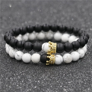 Dettaglio dei ciondoli a corona su bracciali per coppia in lava e marmo bianco