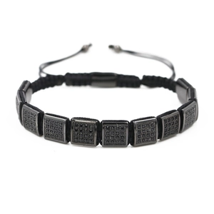 Détail d'un bracelet en corde noire tressée avec breloques carrées en zircon noir