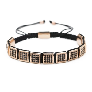 Détail du bracelet tressé noir avec éléments en or rose sertis de zircons noirs brillants