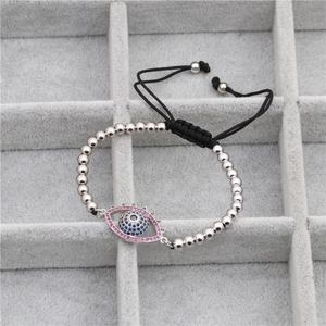 Detail of evil eye charm with blue zircons and black woven cord adjustable bracelet