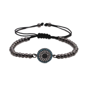 Adjustable woven bracelet with turquoise evil eye pendant and gunmetal beads on white background