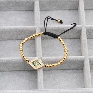 Bracelet ajustable en perles dorées avec breloque œil bleu sur plateau à bijoux gris