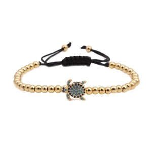 Bracelet tissé avec perles dorées et un pendentif tortue orné de zircons bleus