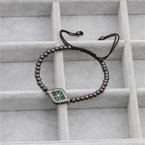 Détail du bracelet perlé avec breloque œil sertie de zircons et cordon réglable noir
