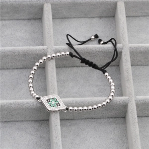 Détail de perles argentées et pendentif œil sur bracelet tressé réglable élégant