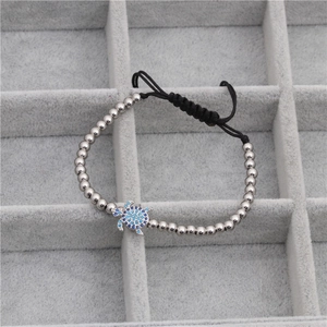 Détail macro du bracelet tortue avec zircons bleus et perles argentées sur velours