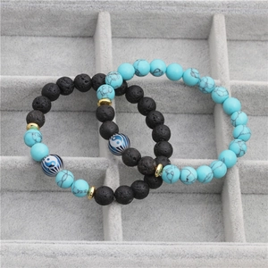 Yin Yang lava stone and turquoise beaded bracelet with gold spacers on grey display