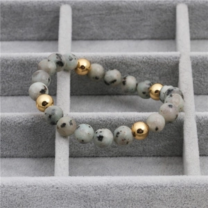 Bracelet en perles de pierre tachetée avec accents dorés polis sur plateau en velours