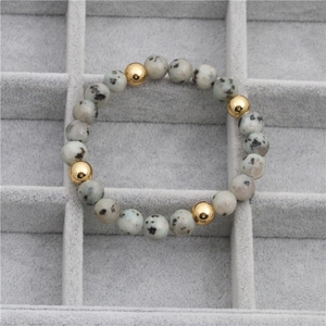Bracelet en perles de pierre tachetées et billes dorées dans un coffret à bijoux