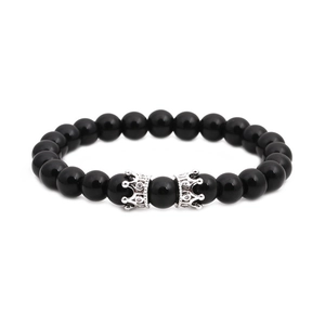 Vue détaillée des perles d'onyx noir et des breloques couronne en argent avec micro-diamants