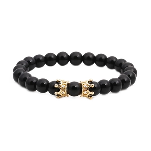 Détail de perles d'onyx noir avec deux charms couronnes dorées sertis de zircons blancs