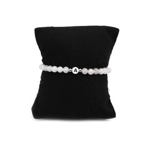 Macro shot of 6mm white turquoise bead bracelet with letter A on a black velvet pillow