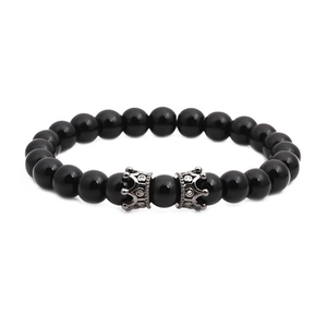 Détail de perles d'onyx noir brillant avec breloques couronne en argent et zircons