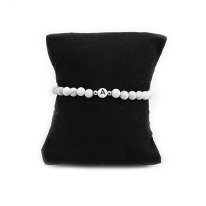 Detailed macro view of 6mm white turquoise beads with a black letter A charm on a bracelet