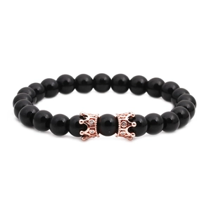 Détail du bracelet en perles d'onyx noir avec deux breloques couronnes en or rose