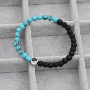 Close-up of Tai Chi pendant with blue marble and matte black beaded stretch bracelet