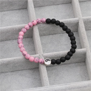 Detail of pink turquoise and matte black beads bracelet featuring a Tai Chi Yin Yang charm