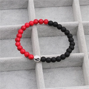 Detailed macro view of red and matte black beaded bracelets featuring a Tai Chi Yin Yang charm
