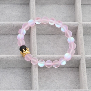 Pink frosted moonstone bead bracelet with a gold crown charm on gray velvet