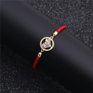 Detail of red woven bracelet featuring a gold pendant with colorful micro-set zircon heart
