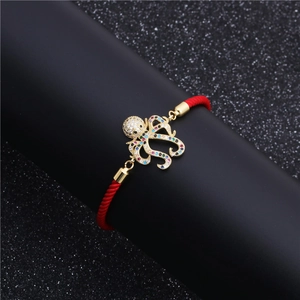 Adjustable red woven string bracelet with a gold-plated octopus charm and colorful zircons