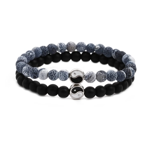 Macro detail of bead bracelets with Tai Chi yin yang charm and matte black stones