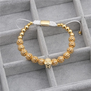 Dettaglio macro del teschio dorato con zirconi incastonati su bracciale intrecciato