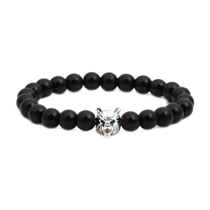 Détail d'un bracelet en perles d'onyx noir avec une tête de loup argentée et yeux verts