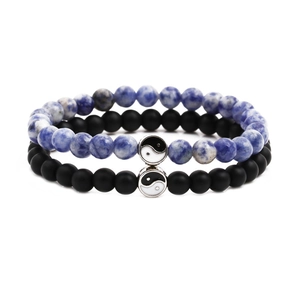 Macro shot of yin yang charms on matte black and blue stone beaded bracelet set